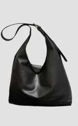 Cartera tipo hobo de color negro, confeccionada en material texturizado con acabado mate. Presenta una correa ajustable integrada al diseño y una silueta curva característica del estilo hobo.