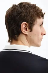 Polo de manga corta confeccionado en piqué de algodón, con cuello y bordes de mangas en color blanco con detalles de líneas negras. Presenta cierre frontal con botones y un corte ajustado.