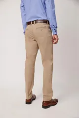 Pantalón de vestir color beige, confeccionado en algodón con spandex. Corte recto, con bolsillos laterales y traseros. Se ajusta a la cintura con cinturón de cuero trenzado en tonos azul y beige.