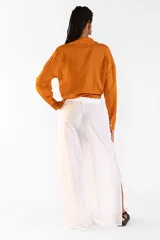 Camisa de algodón color tostado, de manga larga, con cuello camisero, botones frontales y detalle de lazo ajustable en la cintura.