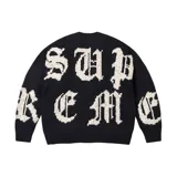 Sweater de punto negro con diseño de letras grandes en color blanco y estilo gótico que forman la palabra Supreme.