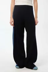 Pantalón de punto de pierna ancha, color negro con franjas laterales en tono azul. Presenta cintura elastizada y un diseño holgado que aporta comodidad.