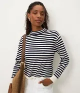 Sweater de punto de manga larga, con cuello mock (cuello alto corto) y puños en color crema. Presenta un patrón de rayas horizontales anchas en azul marino y blanco.