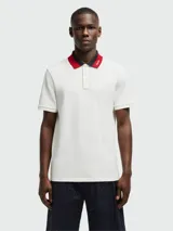 Polo de piqué de algodón color blanco, con cuello clásico a dos tonos (azul marino y rojo) y tapeta de dos botones.