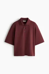 Remera polo de corte holgado confeccionada en piqué de algodón, con mangas al codo, hombros caídos y cuello acanalado. Presenta tapeta con botones y bajo recto con aberturas laterales.