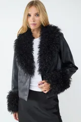 Campera corta de efecto cuero con cuello y puños amplios de piel sintética negra. Presenta un diseño de corte recto y cierre frontal oculto.