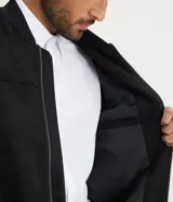 Chaqueta bomber azul marino lisa, con cierre frontal, cuello redondo y bolsillos laterales.