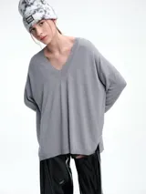Sweater de punto color gris, con escote en V profundo, hombros caídos y diseño holgado de corte relajado.