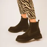 Botas estilo Chelsea de cuero color marrón, con paneles elásticos laterales negros, presillas traseras y suela chunky de goma negra con plataforma dentada.