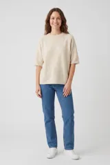 Sweater de punto color beige, con cuello redondo y mangas medias raglán.