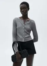 Cardigan de punto acanalado en color gris, con cuello redondo y cierre frontal de botones. Presenta un diseño recto y mangas largas.