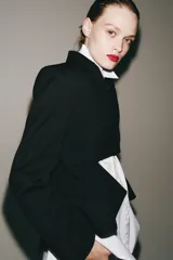 Blazer asimétrica de Zara Woman Collection, confeccionada con mezcla de lana. Presenta cuello solapa, manga larga con botones, cierre frontal con un botón y bajo asimétrico con abertura. Incluye forro interior a tono.