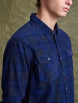 Camisa de pana color azul marino, con mangas largas, cuello clásico y dos bolsillos frontales con solapa y botón.