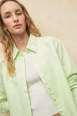 Camisa blanca de algodón con cuello clásico y mangas largas. Detalle de tachas plateadas en el cuello.