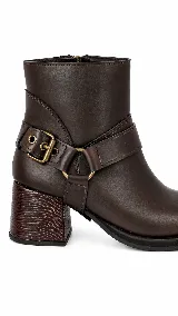 Botas de caña baja en cuero color marrón oscuro, con taco cuadrado y punta redondeada. Presentan un estribo desmontable con hebilla metálica decorativa en el tobillo.