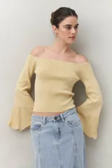 Top tejido negro con escote off shoulder y mangas largas acampanadas con terminación trabajada.