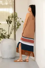 Vestido tejido en hilado de algodón con flecos de gamuza color tostado, con rayas horizontales en el ruedo en tonos negro, blanco, ladrillo y celeste.