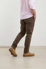 Pantalón de vestir verde oliva, de corte slim fit, sin pinzas, con bolsillos laterales y traseros. Se ajusta a la cintura con cinturón de cuero marrón.