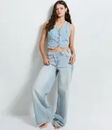 Pantalón wide leg de tiro medio confeccionado en denim de algodón. Presenta un diseño de cintura cruzada con cierre tradicional, trabillas para cinturón y bolsillos funcionales.