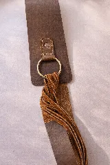 Faja de diseño estructurado confeccionada en una combinación de napa lisa y gamuza negra. Presenta un cierre frontal con argolla metálica plateada y detalles de flecos laterales.