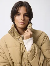 Campera puffer de nylon color negro, con cuello alto, cierre frontal con cremallera y botones a presión. Presenta bolsillos frontales con solapa y diseño acolchado.