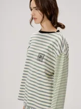 Remera manga larga de corte oversize y cuello redondo, con diseño a rayas horizontales en tonos claros y verde militar, y detalle de bordado frontal.