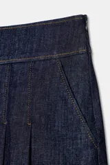 Falda corta de denim azul oscuro, tiro medio, con tablas frontales y costuras a contraste.