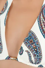 Top de bikini halter con estampado paisley en tonos azules, rojos y marrones sobre fondo blanco. Cuenta con tiras para atar al cuello y en la espalda, y detalle de argolla metálica en el centro con cordones ajustables terminados en terminales metálicas.