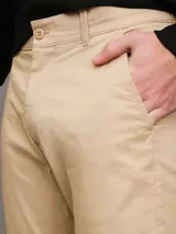 Pantalón chino color beige confeccionado en sarga de algodón elástica suave, de corte regular y pierna estrecha en el tobillo.