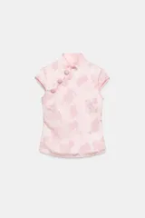 Top satinado jacquard color rosado, con cuello mao, manga muy corta y cierre lateral con cremallera oculta. Presenta detalle de botones decorativos tipo nudo chino en el delantero y diseño con estampado floral sutil.
