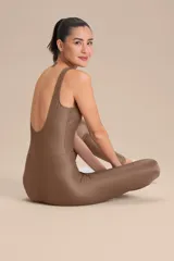 Jumpsuit largo de diseño ajustado con escote redondo y espalda descubierta, confeccionado en tejido satinado con textura acanalada. Presenta copas extraíbles y tecnología de compresión media que se adapta al cuerpo.