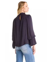 Blusa Tahari de gasa satén color violeta oscuro, con cuello alto fruncido y mangas largas abullonadas. La espalda tiene una abertura central con cierre de botón.