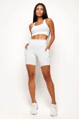 Conjunto deportivo de mujer compuesto por un top de diseño nadador y un biker de tiro alto. Ambas prendas son de color negro, confeccionadas en poliamida de alta performance con detalles reflectivos, bolsillos funcionales y recortes estratégicos para mayor comodidad y ajuste durante el entrenamiento.