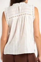 Blusa sin mangas de algodón color blanco, con cuello redondo, detalles de encaje y diseño fruncido en el frente.