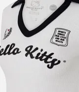 Top corto de tejido piqué, color blanco, con cuello polo y escote en V ribeteado en negro. Presenta mangas cortas con ribete negro y parches bordados de Hello Kitty en el pecho.