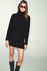 Vestido corto de punto con cuello subido, manga larga y sisa ancha. Presenta un detalle de costura vertical marcada en el centro del delantero y acabados en rib en cuello, puños y ruedo.