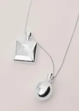 Collar largo de metal plateado con dije doble en forma de botella.