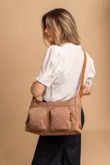Bandolera de tafeta impermeable color beige, con dos bolsillos frontales con cierre y correa regulable. Diseño práctico y liviano ideal para uso diario.