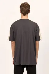 Remera oversize Billabong de color negro, con cuello redondo en tono beige y detalles de bandas beige en los hombros y mangas. Cuenta con un pequeño estampado frontal con el logotipo de la marca.