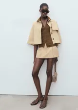 Jersey de punto fino color marrón, con cuello camisero, cierre frontal con botones y diseño entallado de manga corta.