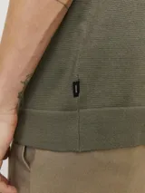 Polo de punto de manga corta en color verde oliva, con cuello clásico y cierre frontal parcial con cremallera. Presenta un tejido estructurado y corte regular.