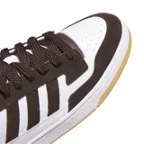 Championes urbanos Adidas modelo Rapid Court Low, con diseño de corte bajo. Presentan una combinación de colores marrón oscuro y blanco, con las icónicas tres tiras laterales en marrón. Cuentan con una entresuela blanca y una suela de goma color caramelo.