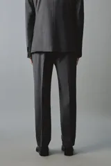 Pantalón de traje regular fit color gris oscuro, confeccionado en tejido con lana, con bolsillos frontales y bolsillos traseros de doble vivo con botón. Cierre frontal con cremallera y botón.