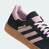 Championes Adidas modelo Handball Spezial, con capellada de gamuza en color negro y detalles en rosa pastel en las tres tiras, cordones y talón. Presenta una suela de goma color caramelo con el logo de la marca grabado en el lateral.
