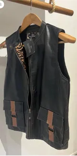 Chaleco de cuero sintético color negro, con cuello alto, cierre frontal y bolsillos frontales con solapa y detalles en cuero marrón. Posee forrería con estampado animal print.