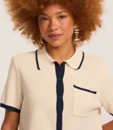 Blusa color crema con cuello inglés y detalles en azul marino, de punto más sostenible, en modelo comfort. Posee cuello inglés, manga corta, abotonado delantero, bolsillo y detalles contrastantes.