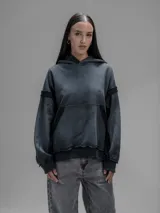 Hoodie oversize de corte crop en color gris oscuro, confeccionado en algodón rústico. Presenta un diseño con costuras expuestas, efecto de desgaste y detalles de roturas en los bordes, incluyendo puños y ruedo.
