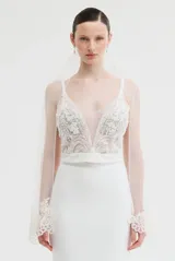 Bustier con escote en V profundo y tirantes finos. Presenta un cuerpo de tul con bordados florales detallados y pedrería, con una base estructurada y una banda lisa en la cintura.