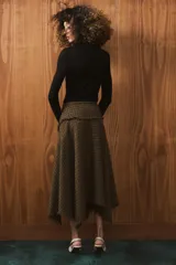 Falda midi de tiro medio con diseño asimétrico y acabados desflecados. Presenta un patrón de cuadros tipo príncipe de Gales en tonos tierra y cierre lateral con cremallera oculta.