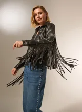 Chaqueta de cuero sintético negra con flecos en la espalda y mangas, cuello camisero, cierre frontal con cremallera y bolsillos laterales.